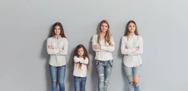 Joyeux sourire maman et les filles debout sur un fond gris . — Photo