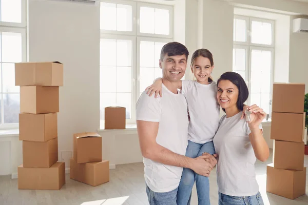 Glückliche Familie mit Schlüssel in der Hand steht in neuem Haus. — Stockfoto