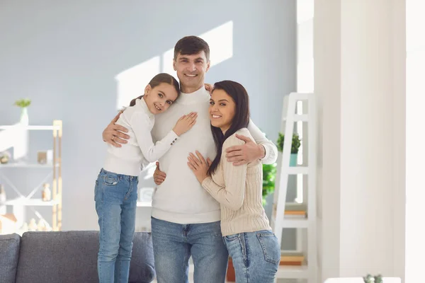 Gelukkig glimlachend gezin. Dochter moeder en vader knuffelen vrolijk in een kamer thuis. — Stockfoto