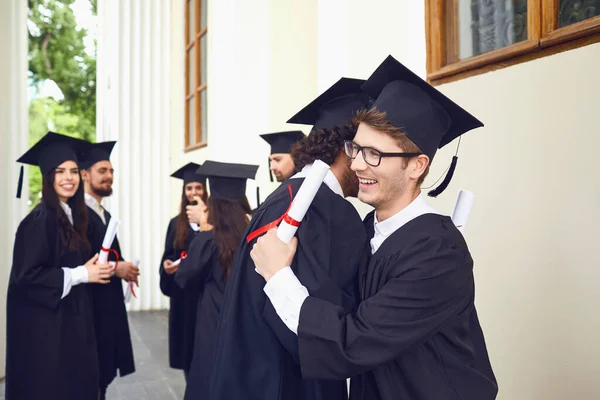 Graduadas con diplomas en sus manos abrazándose — Foto de Stock