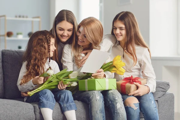 Szczęśliwego Dnia Matki. Córki dzieci dają mamie bukiet kwiatów w domu. — Zdjęcie stockowe
