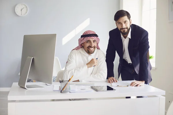 Arab és európai üzletember magabiztosan dolgozik egy fehér irodában. — Stock Fotó
