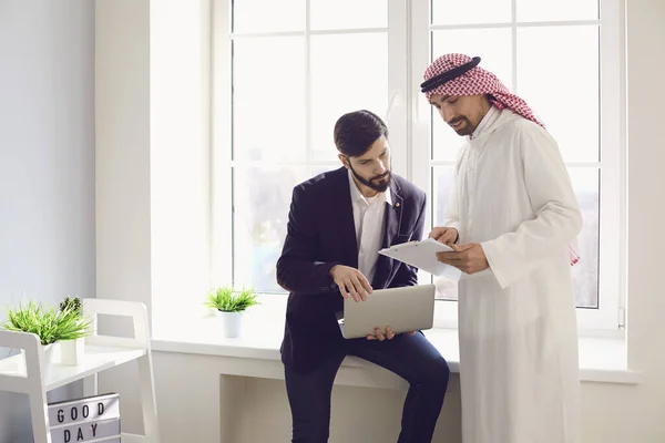 アラブとヨーロッパのビジネスマンは白いオフィスで自信を持って働いています. — ストック写真
