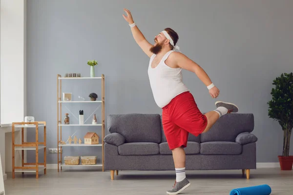 Vtipné červené tlusté muž dělá cvičení, zatímco stojí doma. — Stock fotografie