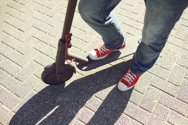 도시 거리에서 전기 스쿠터를 타고 있는 한 남자의 다리. — 스톡 사진