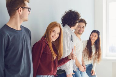 Bir grup gülen arkadaş penceresi olan parlak bir odada dikiliyorlar..