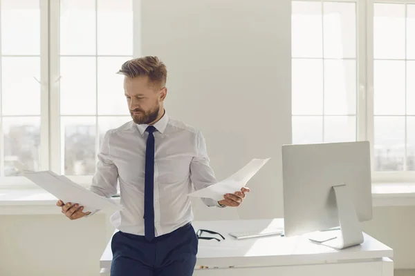 Homme d'affaires blond avec des papiers documents dans les mains debout travaillant dans le bureau — Photo