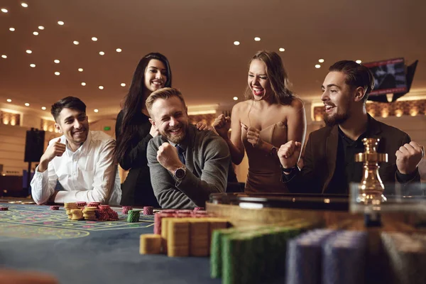 Šťastní lidé sázení v hazardních hrách na ruletě poker v kasinu — Stock fotografie
