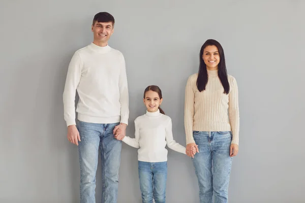 Щаслива сім'я посміхається, стоячи на сірому фоні . — стокове фото