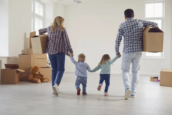 Glad familj med barn flyttar med lådor i ett nytt lägenhetshus. — Stockfoto