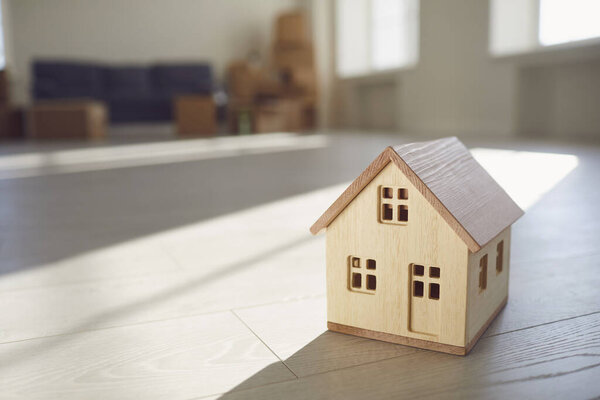 Модель деревянного дома на полу в новом ярком солнечном доме
.