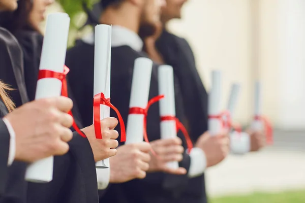 Schriftrollen mit Diplomen in den Händen einer Gruppe von Absolventen. — Stockfoto