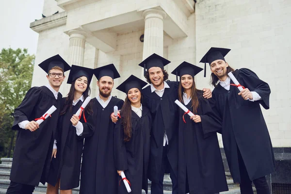 Un gruppo di laureati con le pergamene in mano sorride — Foto Stock