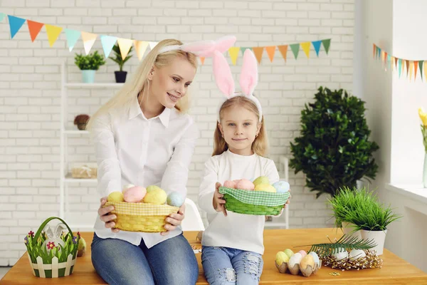 Happy easter. Daughter and mother with rabbit ears decorate Easter eggs sitting at a table — Stockfoto