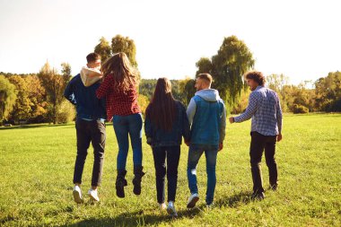 Happy friends walking on green meadow