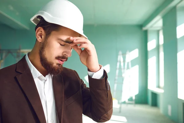 Builder foreman in a white helmet surprised in shock at a construction site indoors — Stock Photo, Image