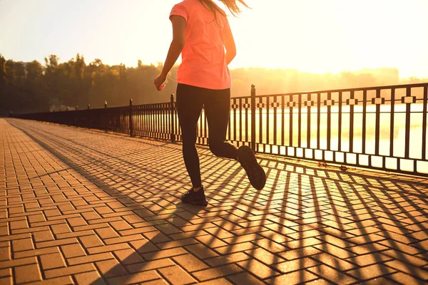Menina corredor corre em um parque junto ao lago ao amanhecer — Fotografia de Stock