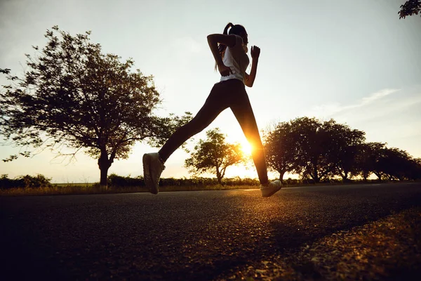 Ragazza corridore corre sulla strada il sole all'alba — Foto Stock