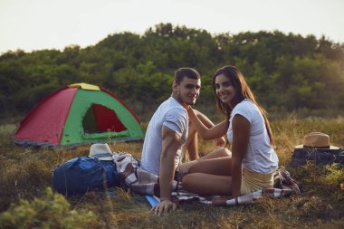 Romantik kamp. Şenlik ateşinin yanında oturan genç bir çift.