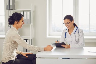 Doctor woman pediatrician gynecologist talking client sitting at a table in a clinic office.