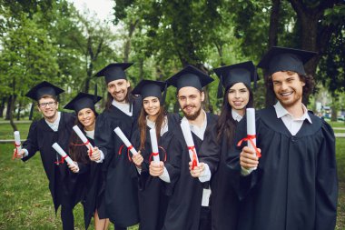 Ellerinde tomarlarla bir grup mezun gülümsüyor.