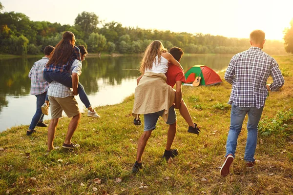 Friends have fun running along the lake on a picnic. — Stock Photo, Image