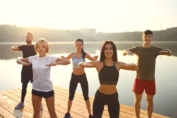 Eine Gruppe aktiver Menschen macht Übungen im Park am See. — Stockfoto