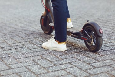 Kasklı genç adam yazın bir şehir caddesinde elektrikli scooter kullanıyor.