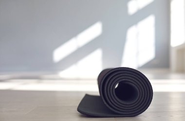 Parlak güneşli bir stüdyonun zemininde siyah yoga minderi..