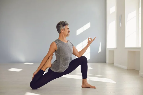 Hombre del yoga. Un hombre está practicando el equilibrio del yoga en una habitación gris. —  Fotos de Stock