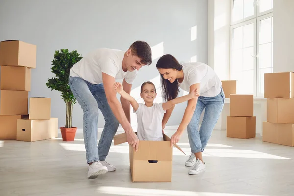 Una familia feliz se divierte jugando con una caja en el suelo en un apartamento nuevo . — Foto de Stock