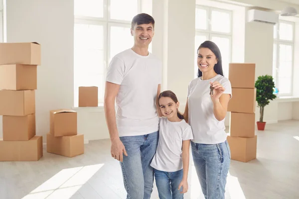 Família feliz com chaves em suas mãos fica em uma nova casa . — Fotografia de Stock