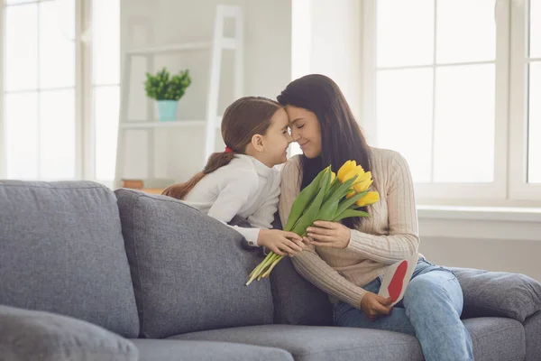 Ευτυχισμένη μέρα μητέρων. Η κόρη συγχαίρει τις αγκαλιές. Η μητέρα του κρατάει ένα μπουκέτο λουλούδια στο δωμάτιο.. — Φωτογραφία Αρχείου