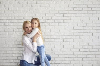 Happy easter. Mother and daughter with rabbit ears smiling against a white brick wall.