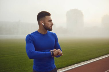Portrait of a young happy male athlete at the stadium in the fog.