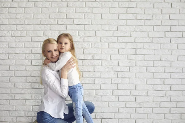Happy easter. Mother and daughter with rabbit ears smiling against a white brick wall. — Stock Photo, Image