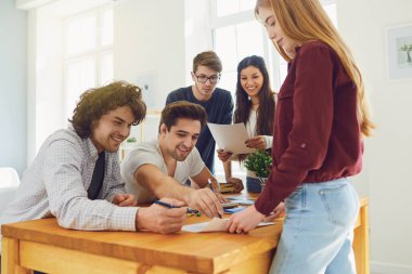Teamwork. Young people analyze discuss business strategies while sitting at a table