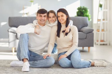 Mutlu gülümseyen aile kucaklaşması evde yerde oturuyor..