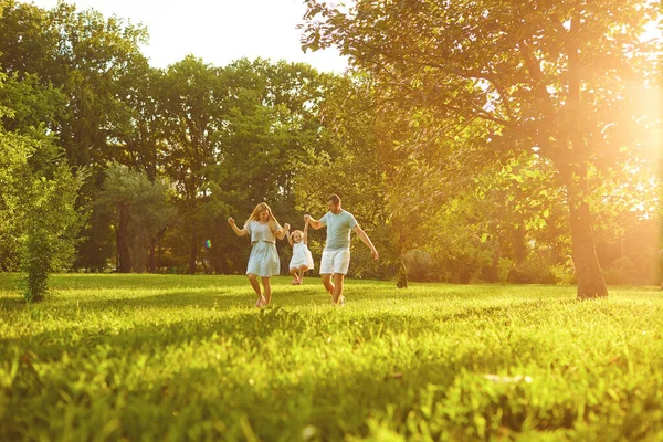 Батьки з дитиною стоять на траві в парку — стокове фото