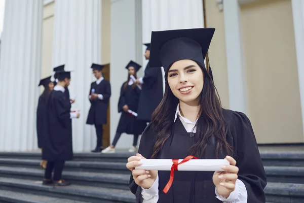 Een meisje afgestudeerd tegen de achtergrond van universitaire afgestudeerden. — Stockfoto