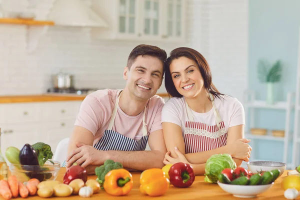 Happy middle couple smiling at a table with fresh vegetables make salad in the kitchen. — Stock Photo, Image