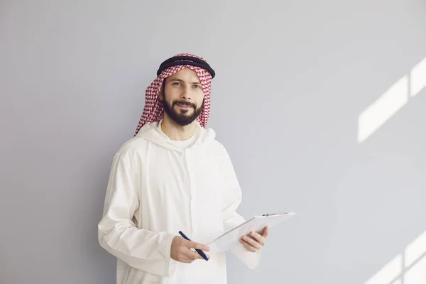 迷人的微笑的arab男子写在剪贴板上的灰色背景 — 图库照片