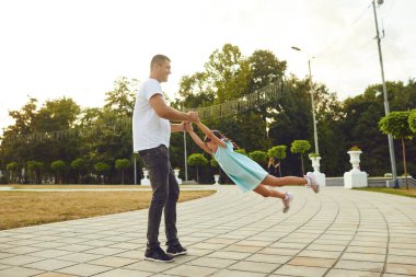 Father and mother having fun throw up a daughter in the street