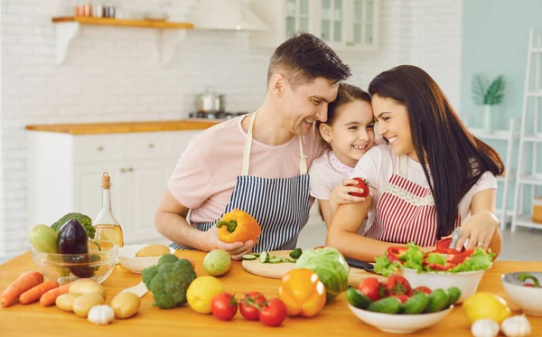 Szczęśliwa rodzina z córką w kuchni z warzywami. — Zdjęcie stockowe