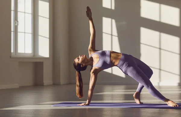 Girl posing in yoga pose in a room at sunrise in the sun. — Stok fotoğraf