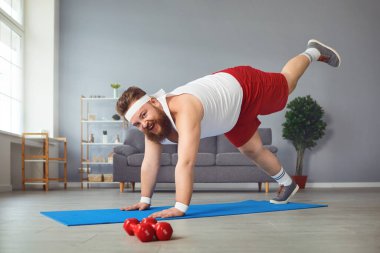 Funny fat man doing yoga exercises in the room.