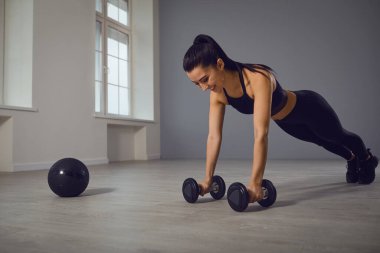 Siyah spor giysili atletik kız kapalı bir odada şınav çekiyor..