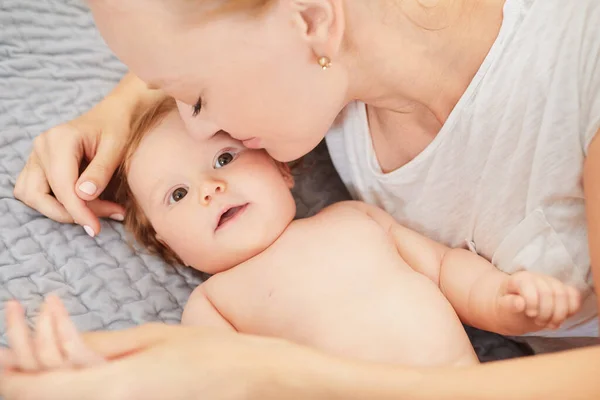 Madre abrazando a su bebé acostado en una cama — Foto de Stock