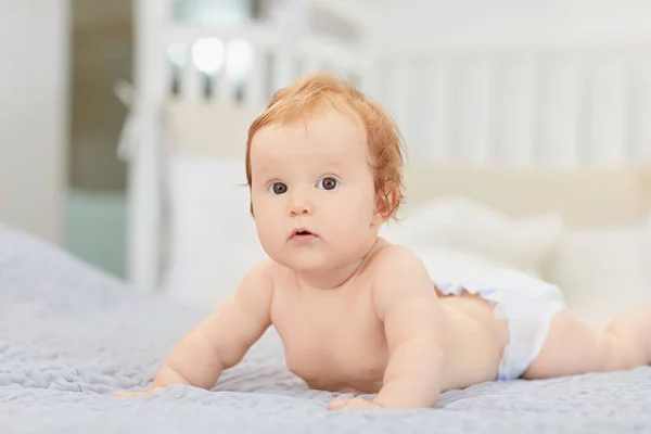 Um bebê sorrindo está deitado em uma cama em um quarto . — Fotografia de Stock