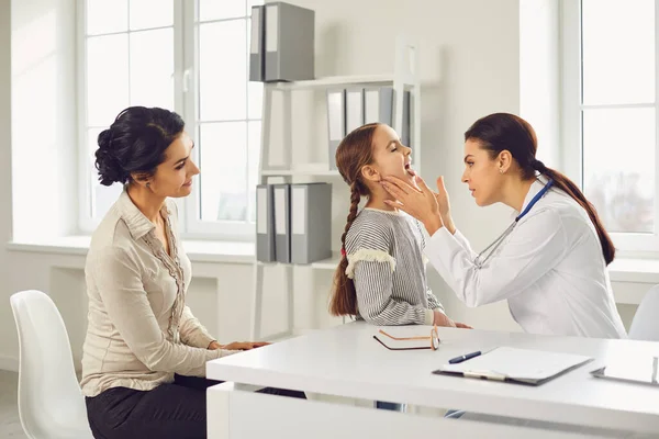 Dokter kinderarts vrouw doet check-up naar kind met met met mam op kliniek kantoor. — Stockfoto